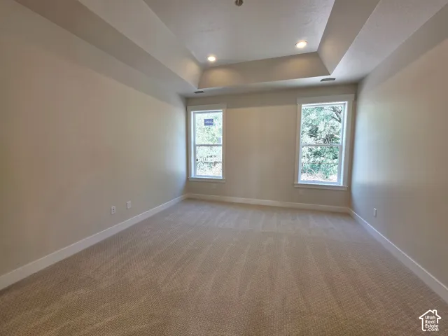 Tray ceiling with recessed lighting, neutral wall paint, two windows, wall-to-wall carpeting, and white trim