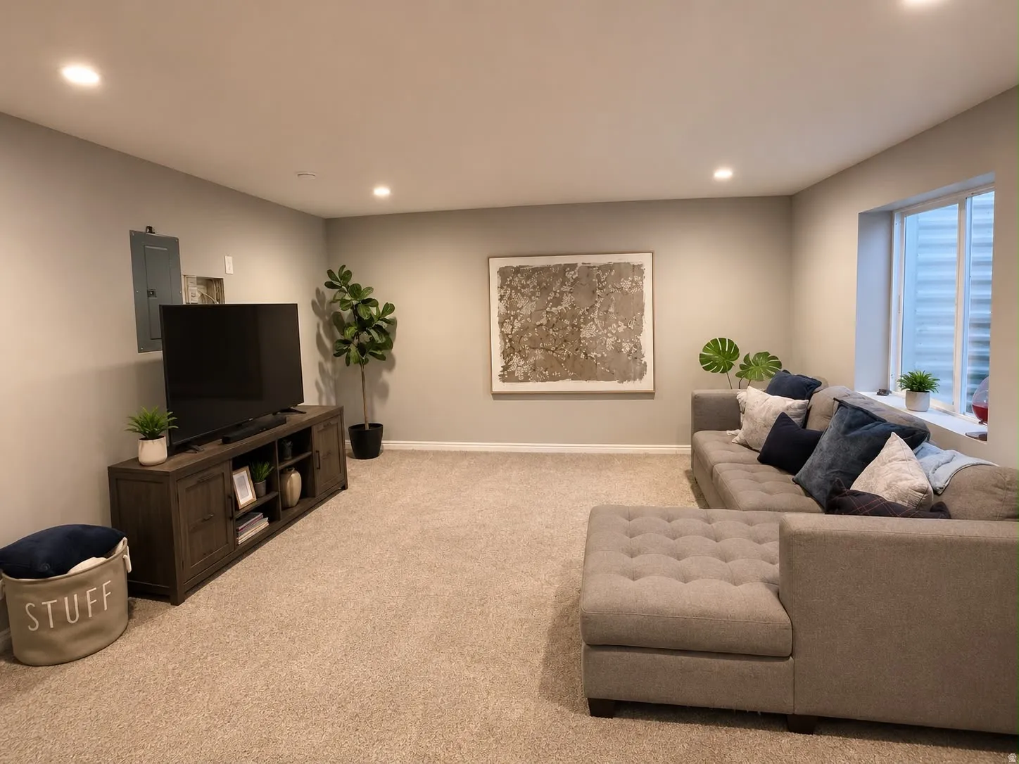Carpeted living space featuring recessed lighting, a neutral color palette, a rectangular window with horizontal blinds, and a built-in electrical panel