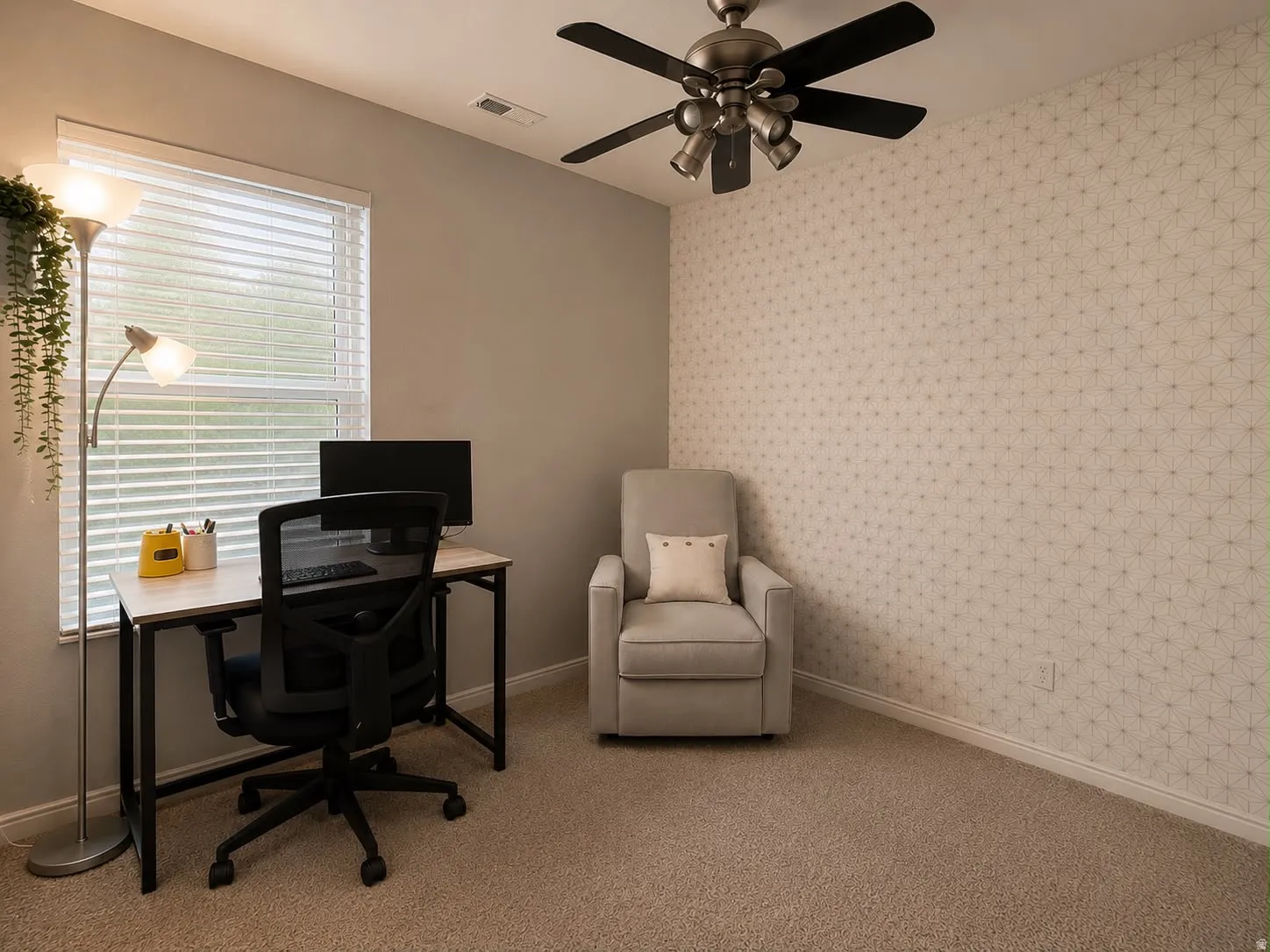 Carpeted room featuring a ceiling fan with integrated lighting, a window with horizontal blinds, and a patterned accent wall