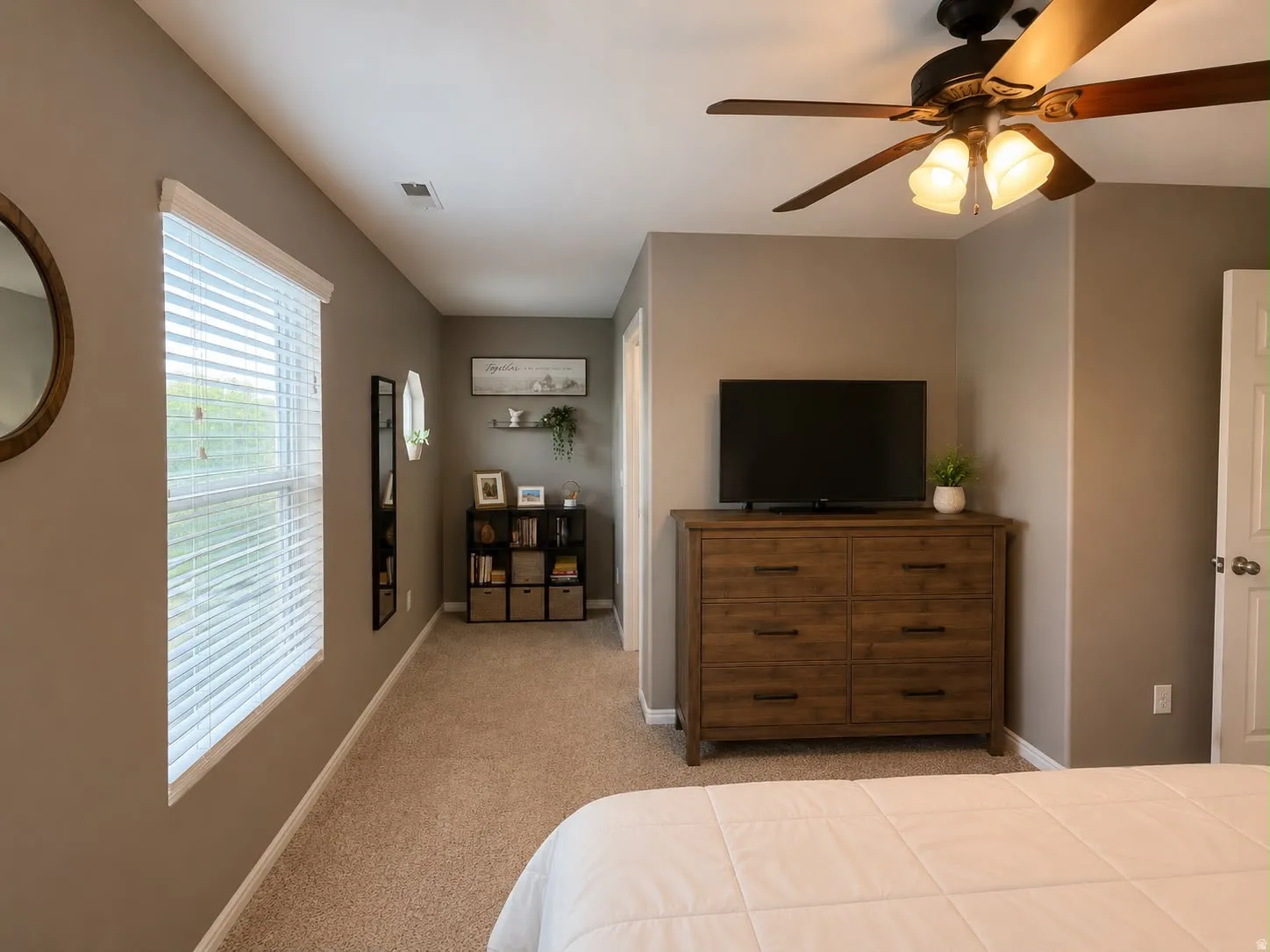 Carpeted room featuring a ceiling fan with integrated lighting, a window with blinds, and a built-in shelf unit