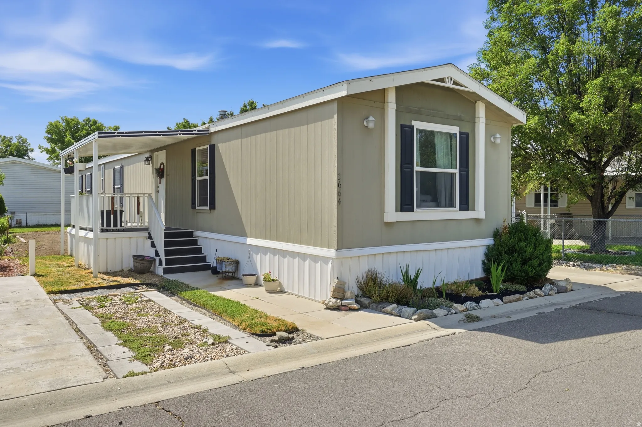 Modern manufactured home featuring light olive siding, white trim, and a covered front porch