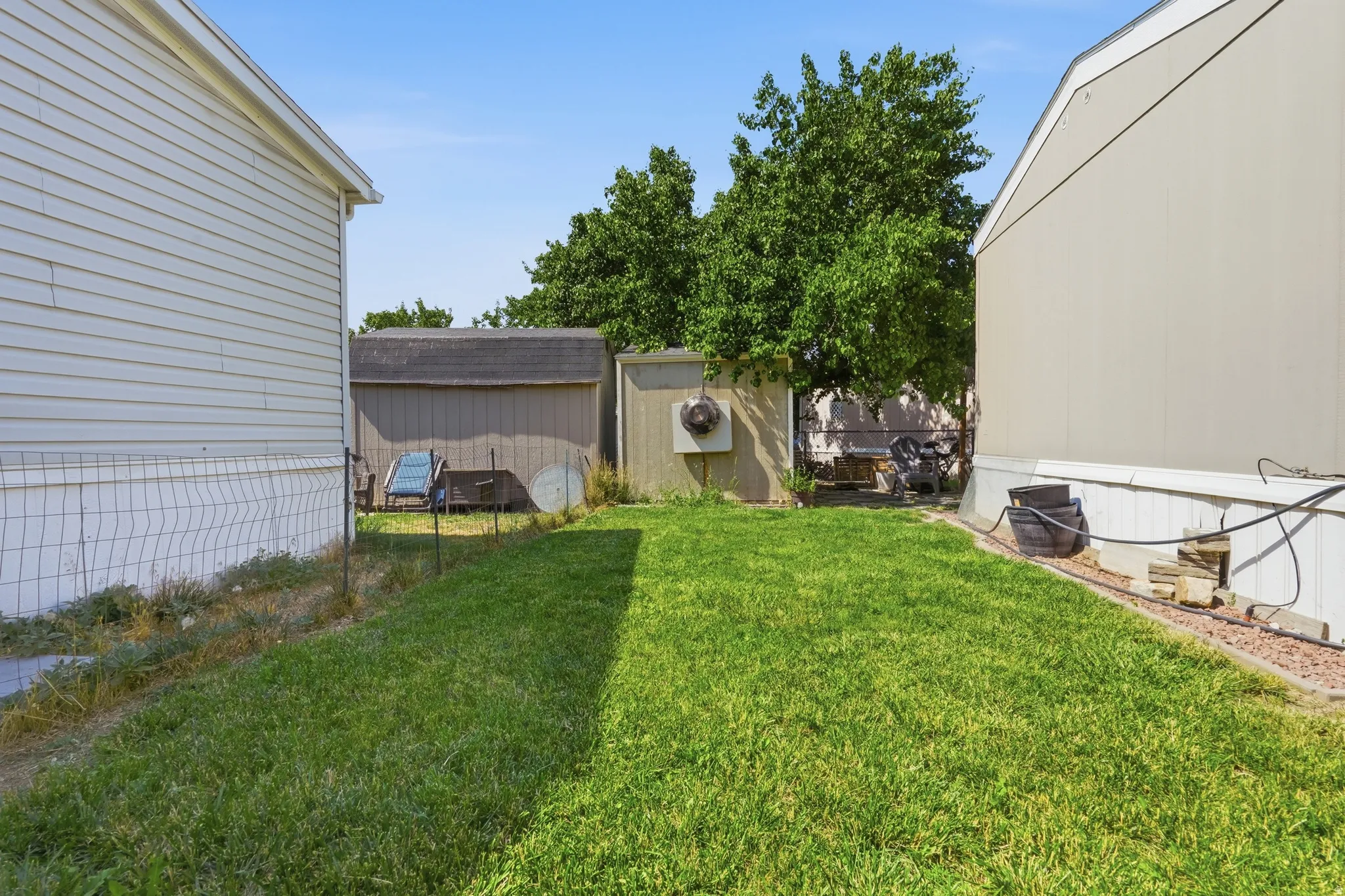 Expansive grass lawn bordered by two structures with horizontal siding