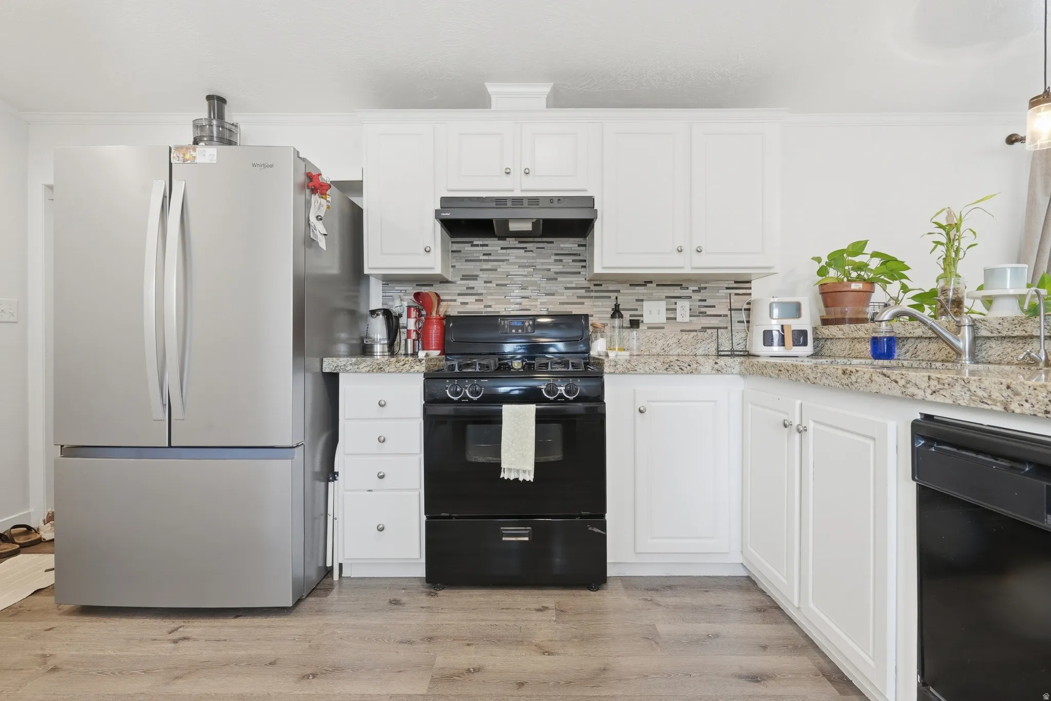Kitchen featuring white cabinetry, stone-finish countertops, and a mosaic tile backsplash
