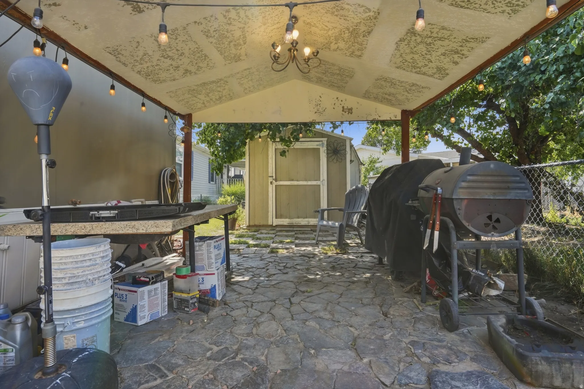 Covered outdoor patio with flagstone flooring, a built-in countertop, string lighting, and an overhead chandelier