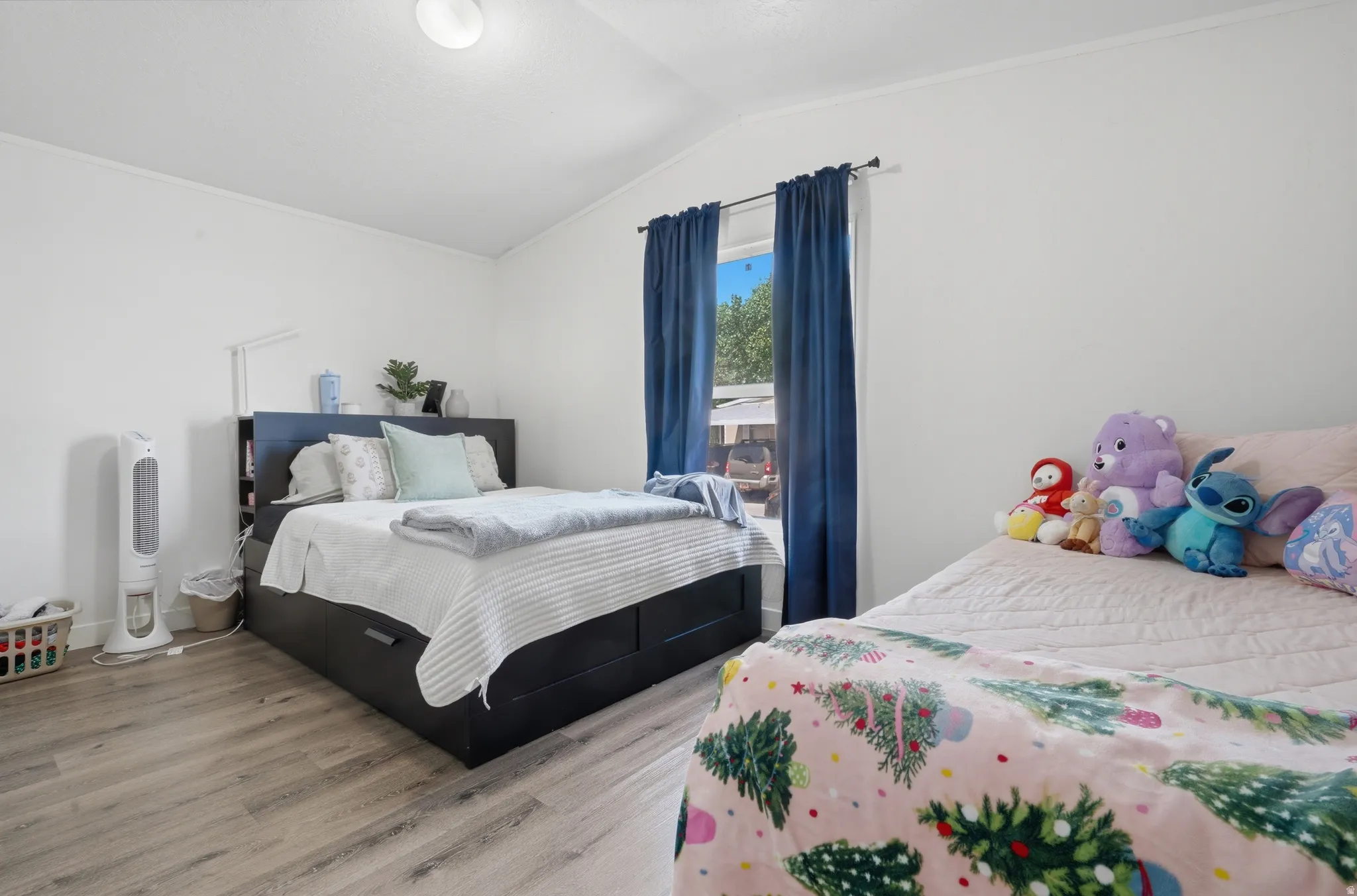 Bedroom featuring light wood-finish flooring, white walls, and a window with dark blue curtains