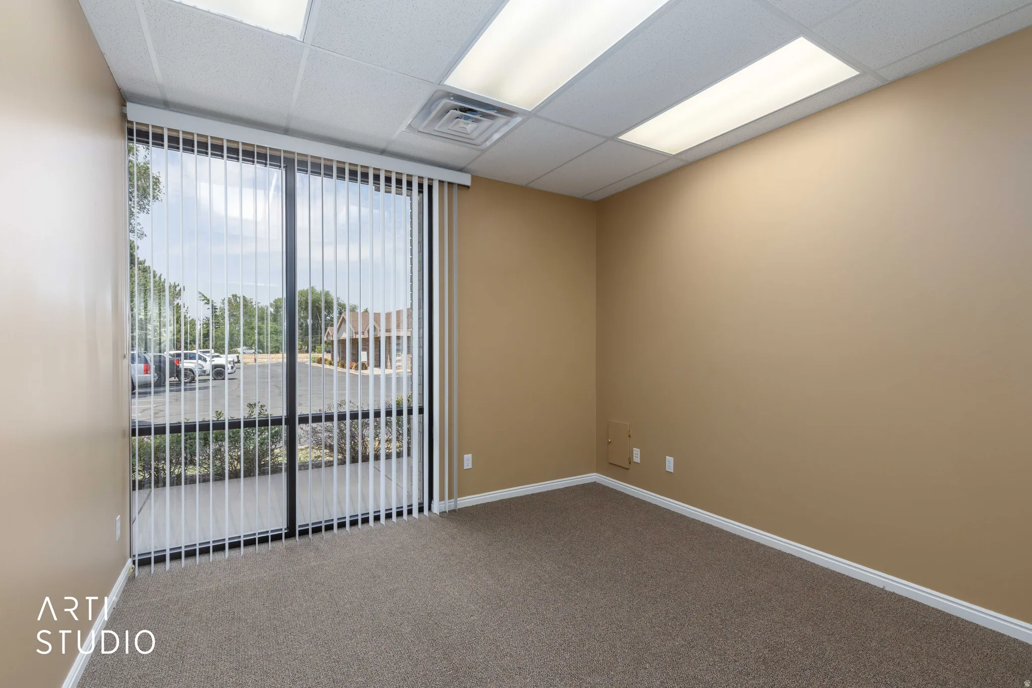 Commercial space featuring expansive window with vertical blinds, neutral wall paint, textured carpet, and recessed ceiling lighting