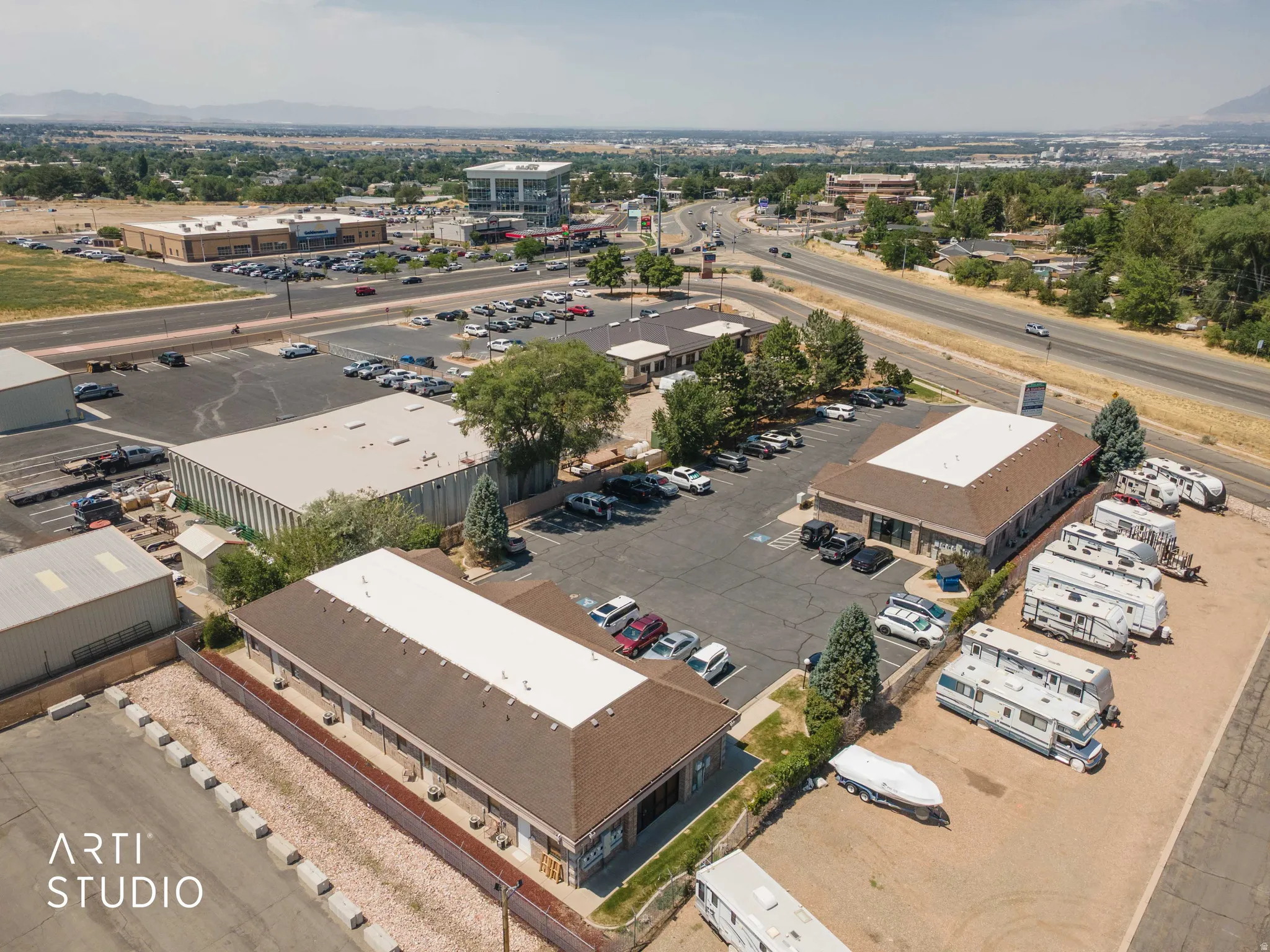 Expansive commercial property featuring multiple buildings, paved parking areas, and convenient access to a main roadway