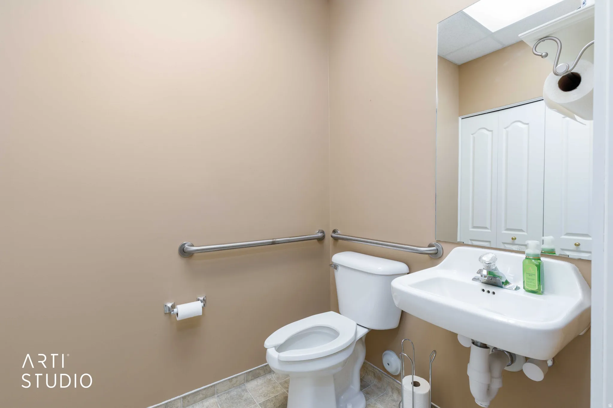 Restroom featuring neutral wall color, tiled flooring, a wall-mounted sink, and grab bars