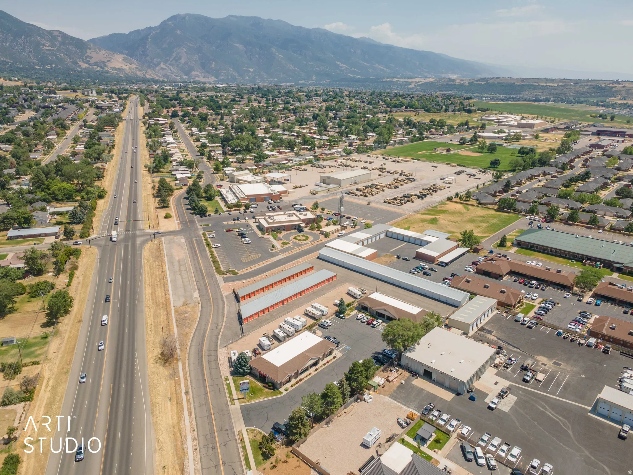 Expansive aerial perspective showcasing a multi-lane highway, commercial properties, and residential areas