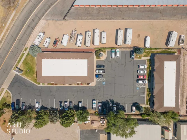 Aerial view showcasing two commercial buildings with brown roofs, extensive paved parking areas, and adjacent storage for recreational vehicles