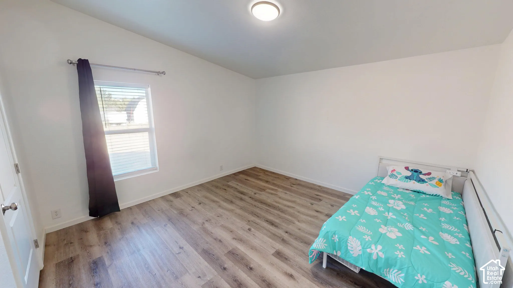 Bright interior space featuring wood-finish flooring, white walls, and a vaulted ceiling