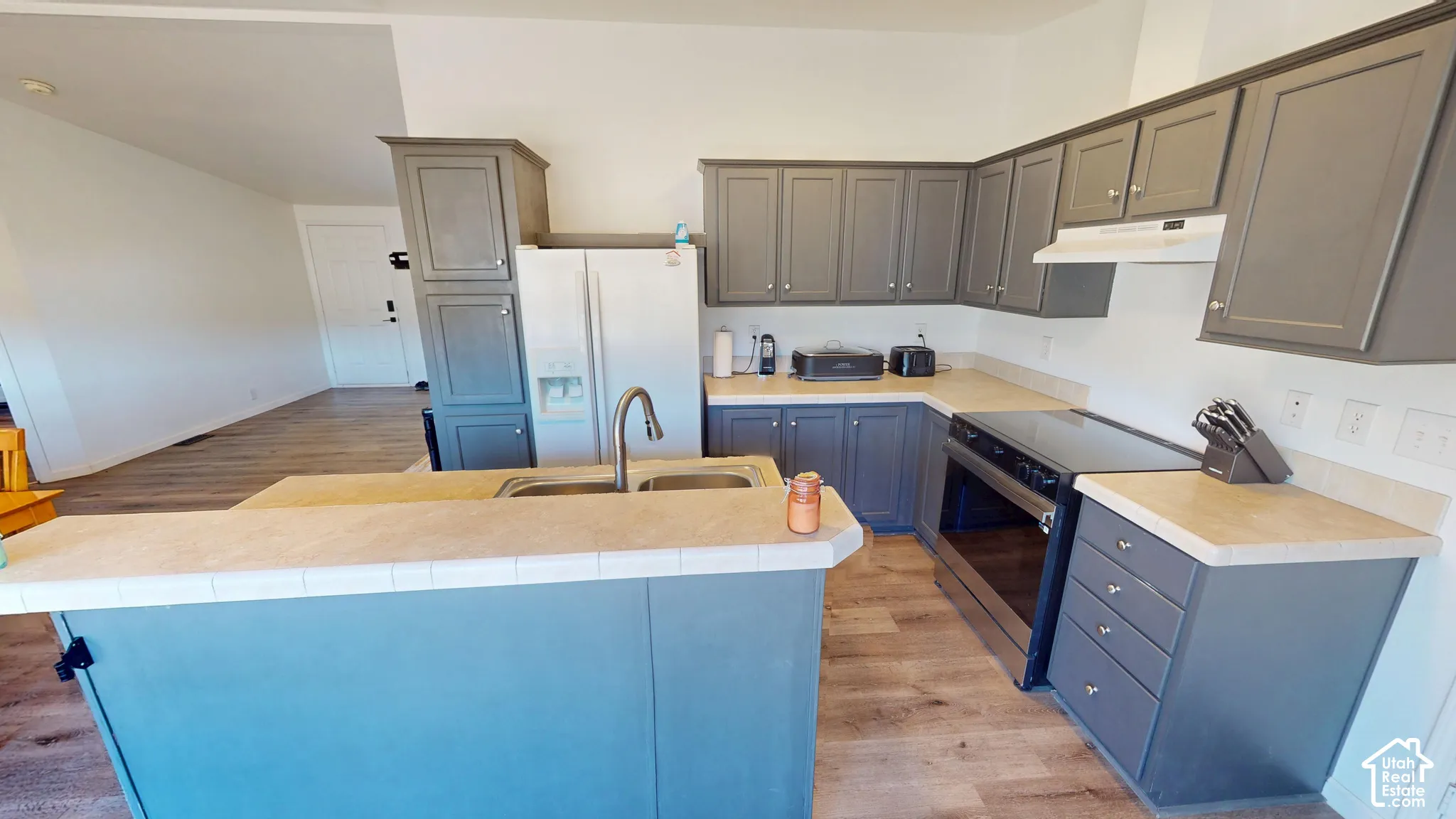 Kitchen featuring wood-finish flooring, grey cabinetry, light-toned countertops, and a stainless steel electric range
