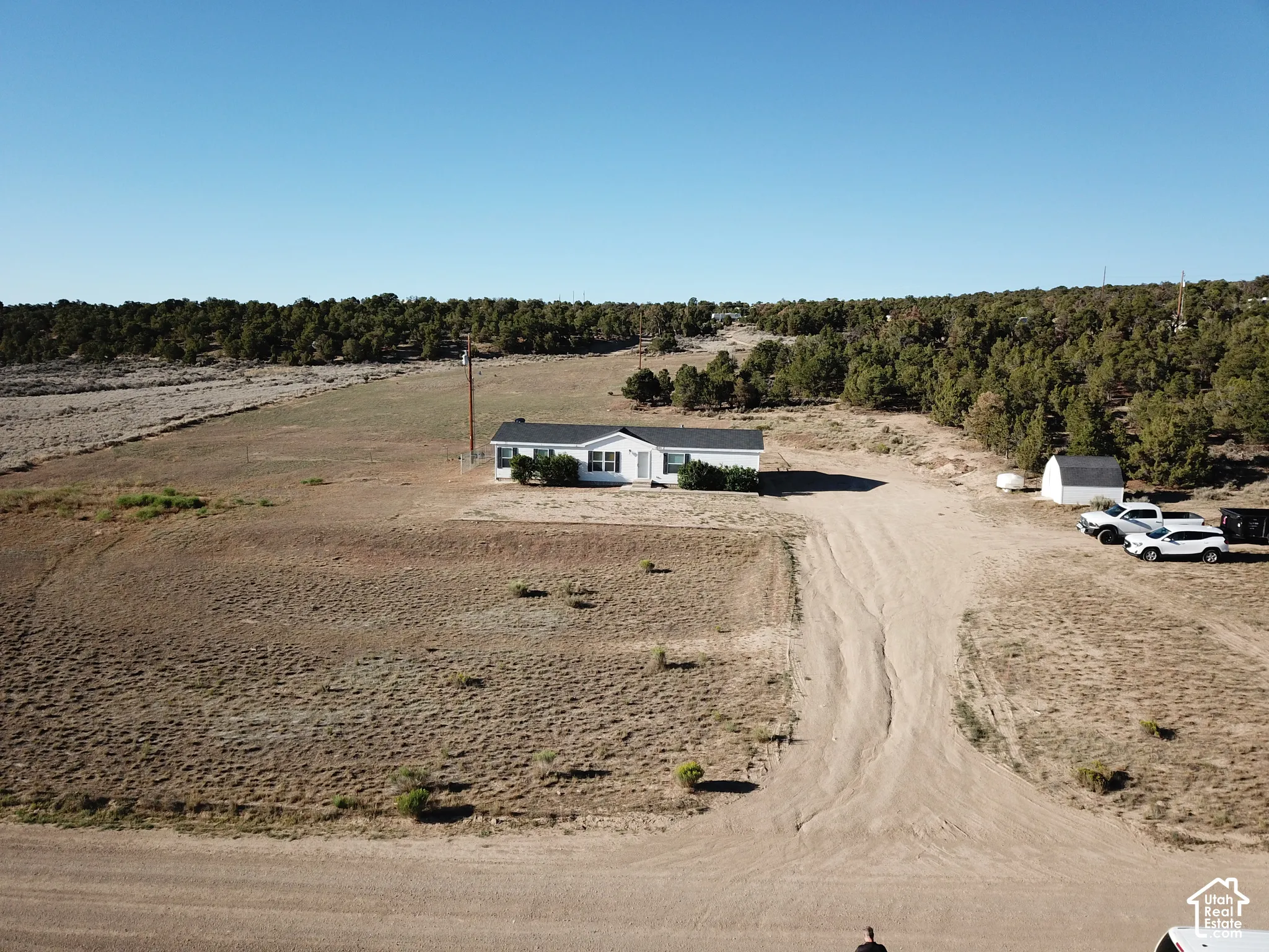 White exterior residence with a dark roofline set on an expansive, arid landscape