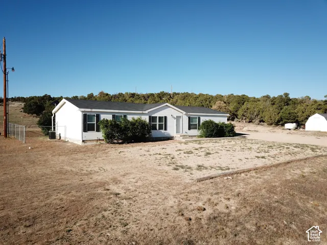 Single-story residence featuring white siding, dark shutters, and a dark shingle roof