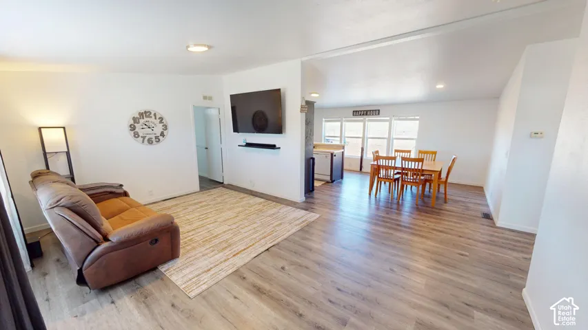 Open-concept living space featuring wood-finish flooring, white walls, and recessed lighting