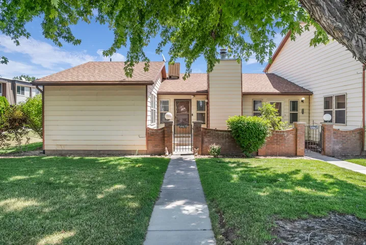 Front exterior featuring a pedestrian pathway, a manicured lawn, and brick half-walls with wrought iron gates