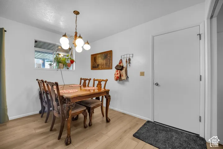 Bright dining space featuring a window, wood-finish flooring, white walls, and a five-light chandelier