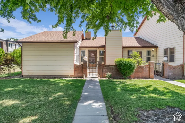 Front exterior featuring a pedestrian pathway, a manicured lawn, and brick half-walls with wrought iron gates