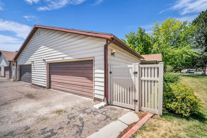 Two-car garage with horizontal siding, brown garage doors, and a wood-finish fence and gate