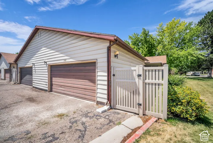 Two-car garage with horizontal siding, brown garage doors, and a wood-finish fence and gate