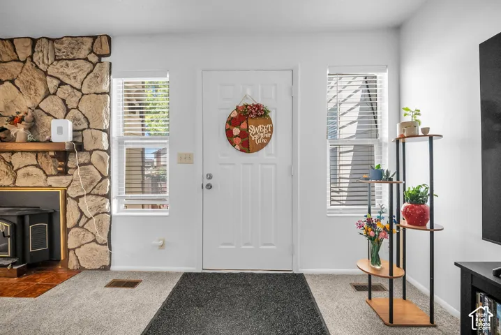 Entryway featuring a stone-clad fireplace with wood mantle, white paneled door, and two side windows with blinds