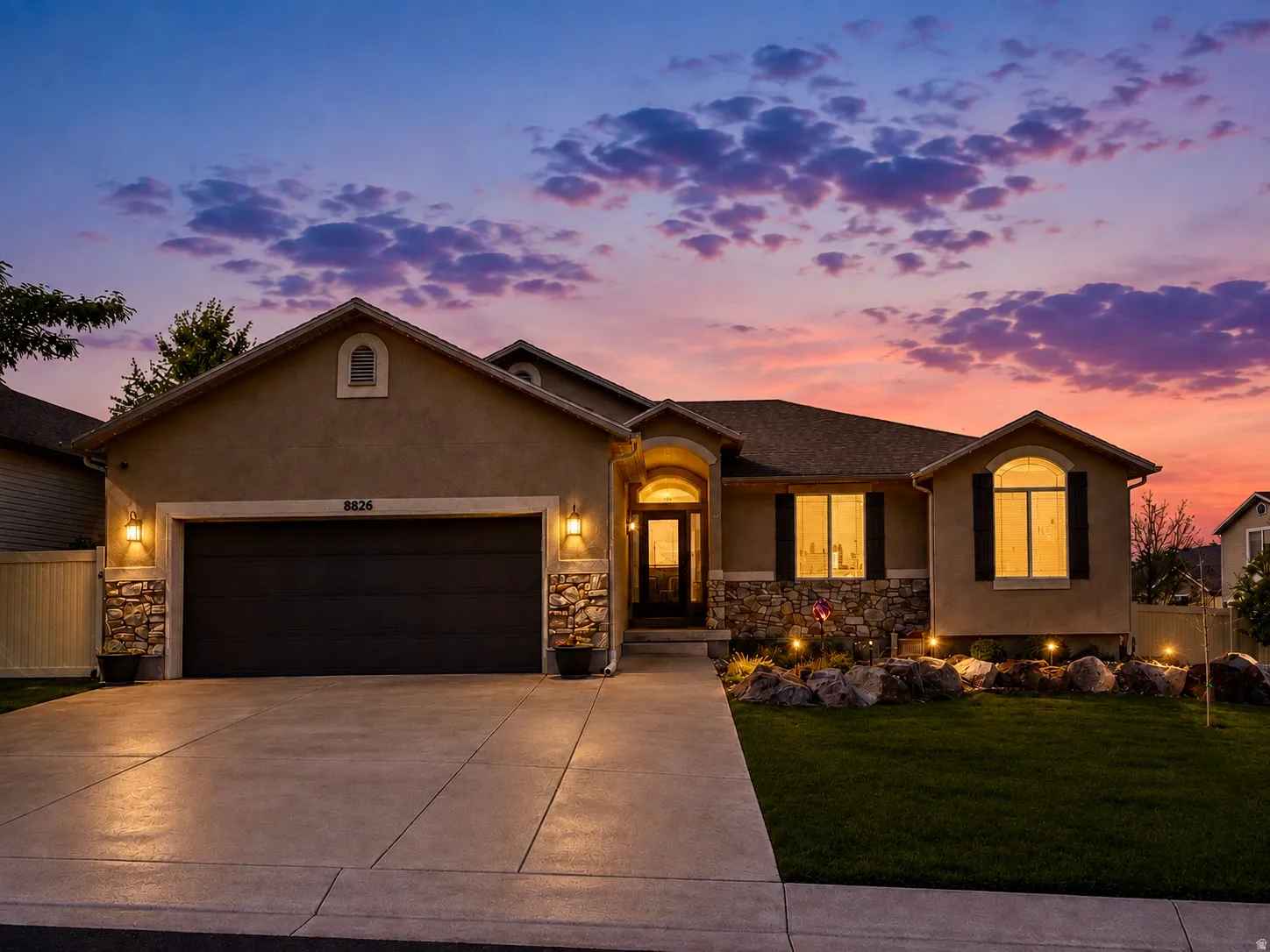 Stucco exterior with stone accents, arched entryway, and dark garage door