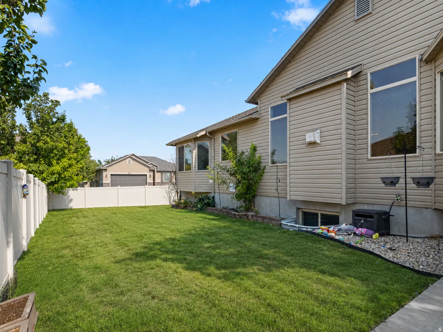 Expansive lawn area enclosed by a white privacy fence