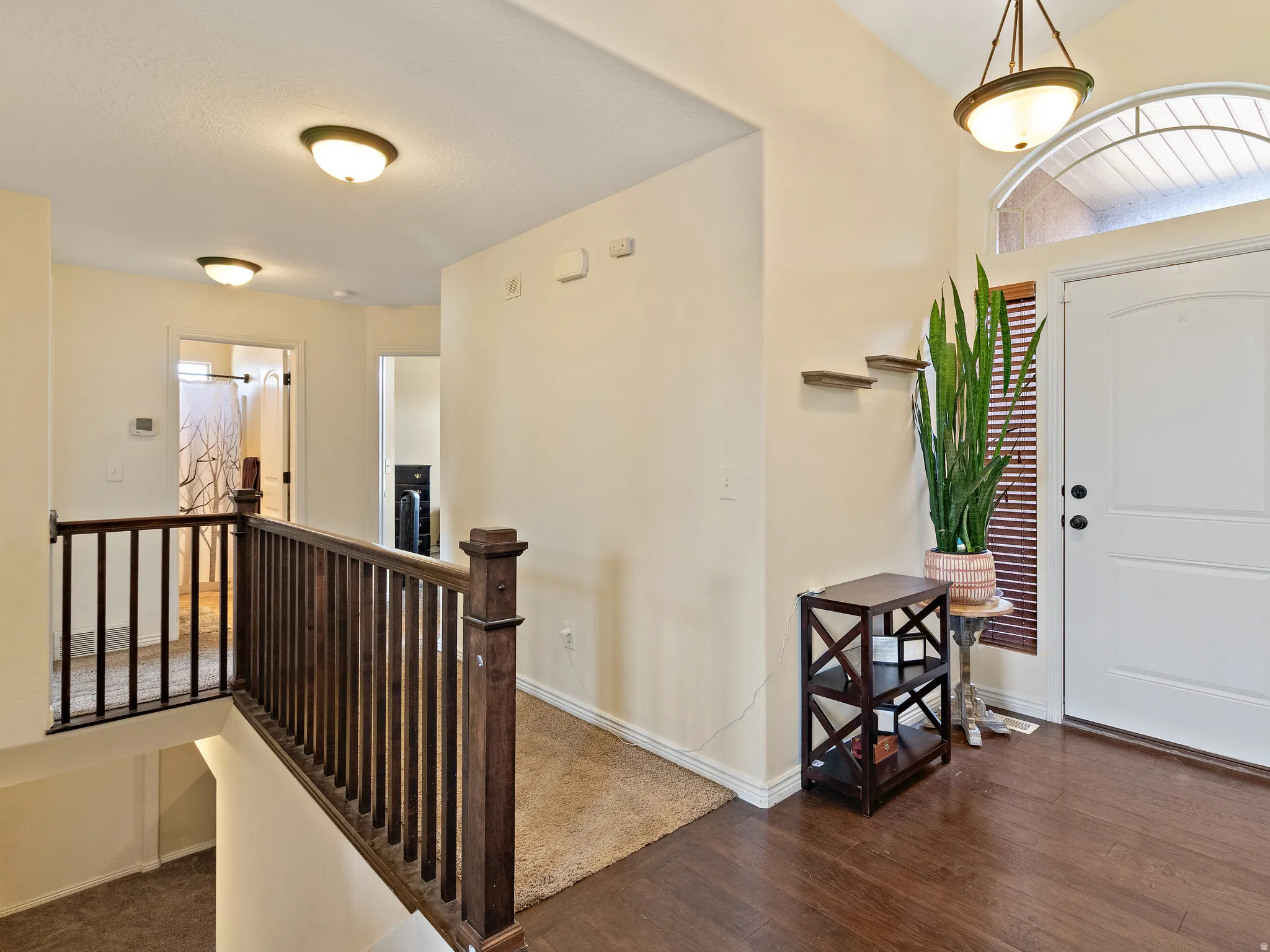 Welcoming foyer with wood-finish flooring, a white entry door, and an arched transom window