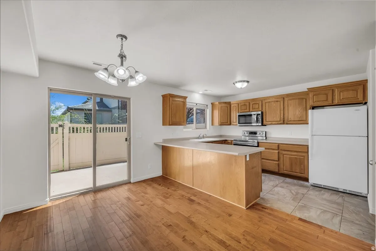 Spacious open-concept kitchen with modern wood cabinetry, wood-finish flooring, and seamless flow into the dining area, complete with a sliding glass door leading to the patio.