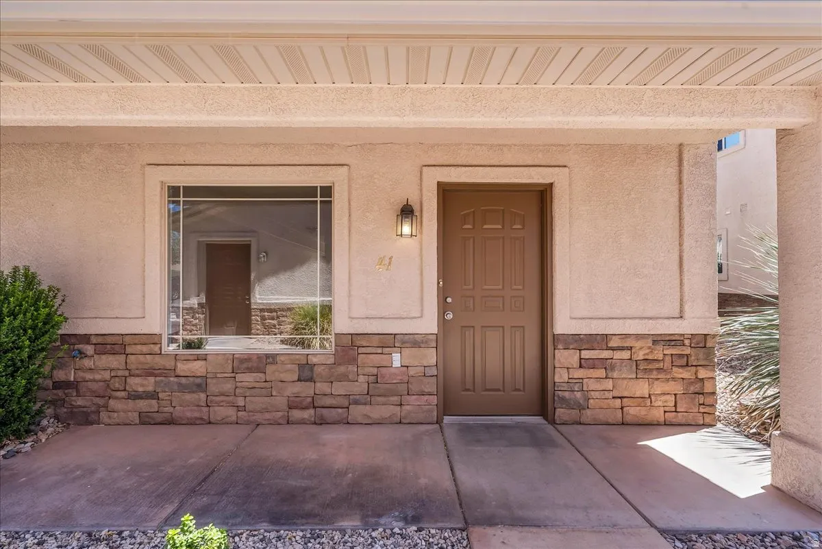 A welcoming, covered entry creates a warm first impression, highlighted by a stucco exterior with stacked stone accents, a paneled front door, and charming grid-style windows.