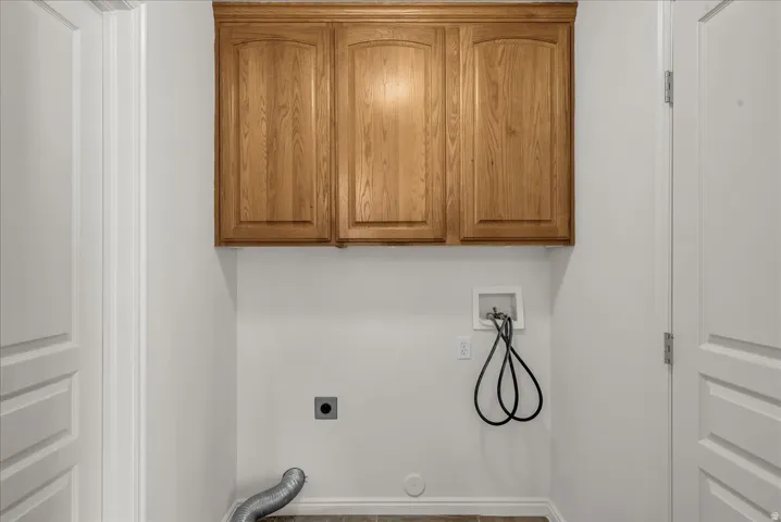Dedicated laundry room with overhead cabinetry and utility hookups, offering added storage and everyday convenience.
