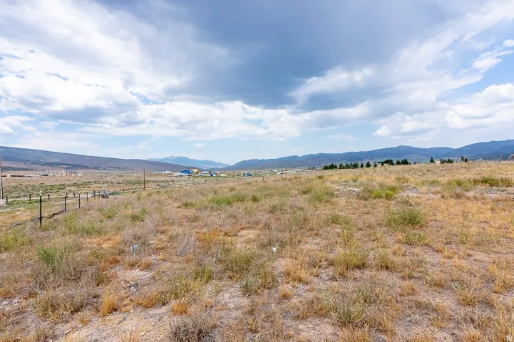 Expansive open land with natural ground cover, offering distant mountain ranges and a partially fenced perimeter