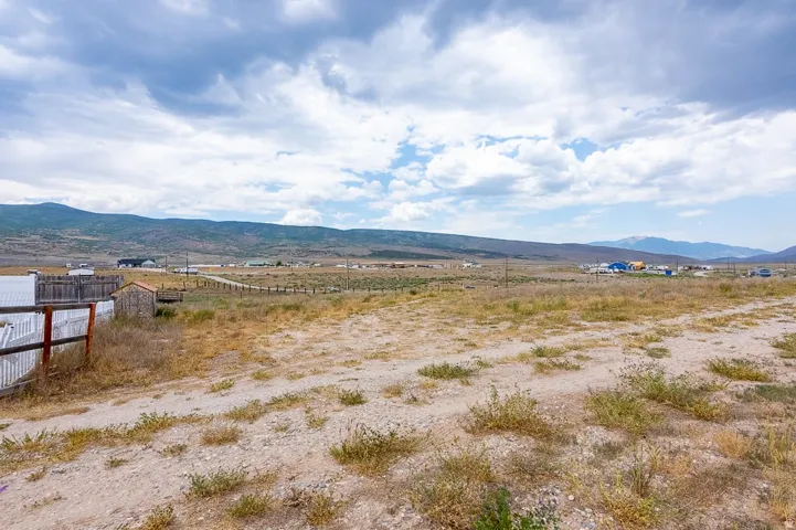 Expansive open land featuring a dirt path, natural ground cover, and a split-rail fence