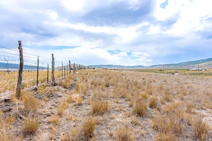 Expansive open land with a perimeter fence featuring wooden and metal posts