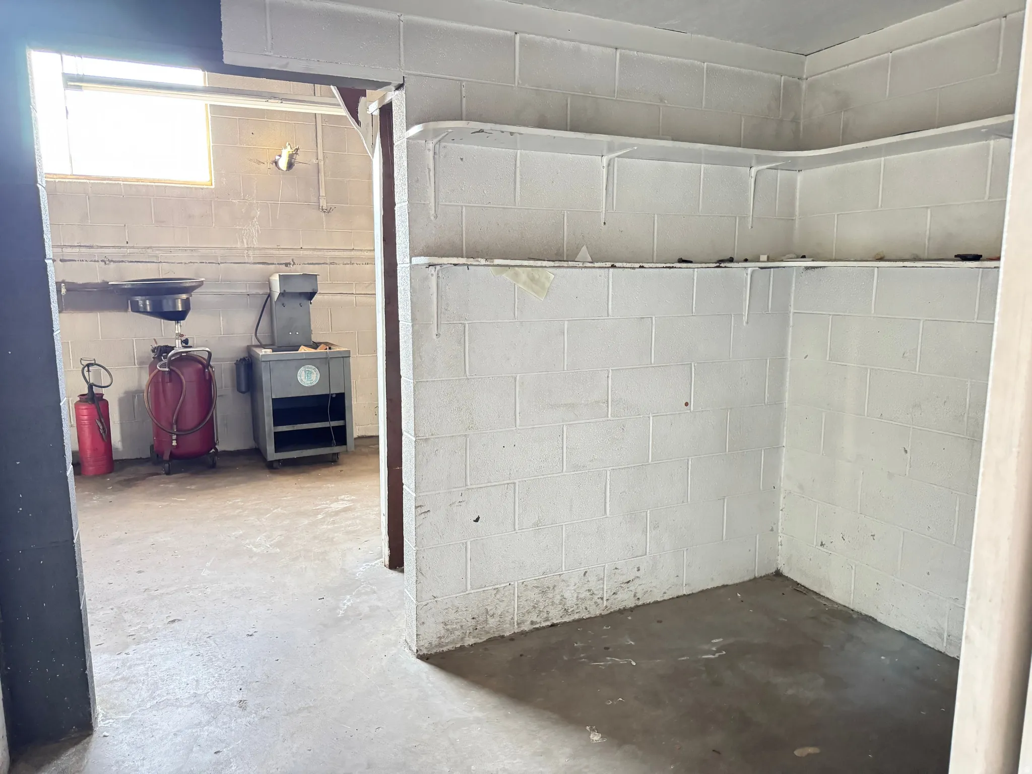 Corner storage area with built-in shelving, concrete block walls, and concrete flooring