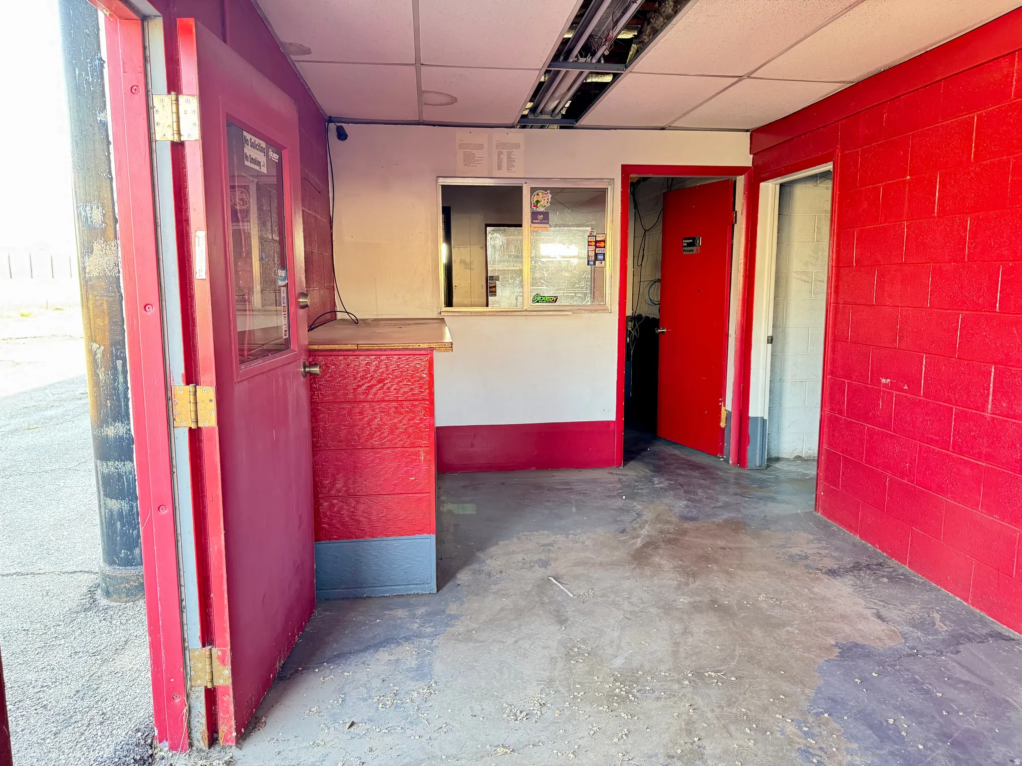 Commercial space featuring a service window, two entry doors, and a concrete floor