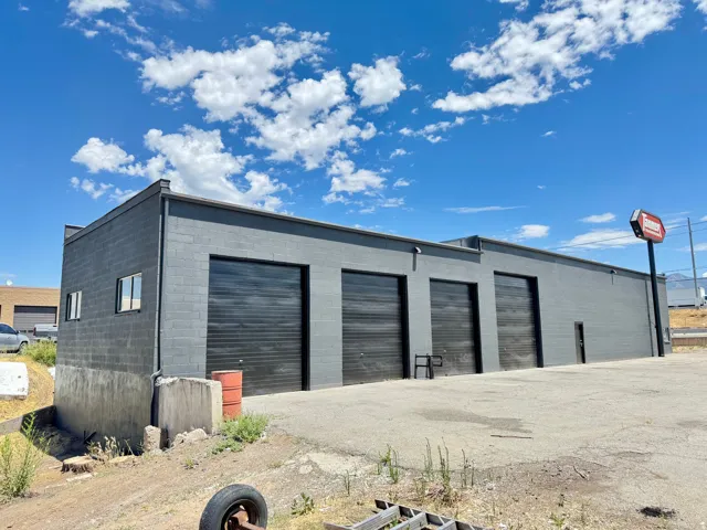 Industrial building featuring a dark gray block exterior, multiple roll-up doors, and a single entry door