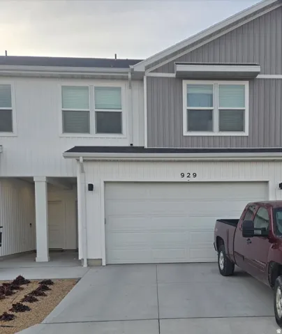 Contemporary townhome exterior featuring a two-car garage, vertical and horizontal panel siding, a covered entry, and a paved driveway