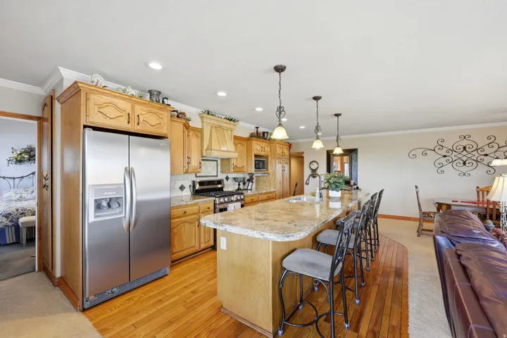 Open-concept kitchen featuring light wood cabinetry, a stainless steel refrigerator, and a gas range