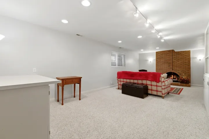Spacious room featuring light-colored carpeting, a brick fireplace, recessed lighting, and track lighting