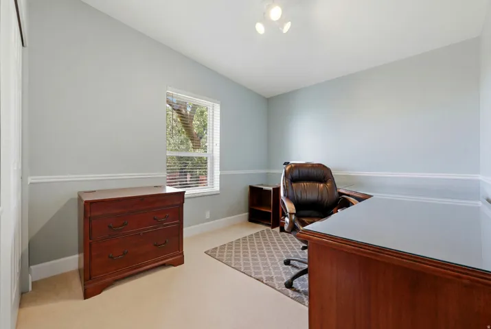 Carpeted room with a single window featuring blinds, light blue walls, and chair rail molding
