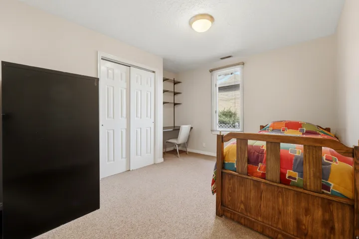 Room featuring neutral wall tones, carpet flooring, a window with exterior visibility, and a built-in desk area with shelving