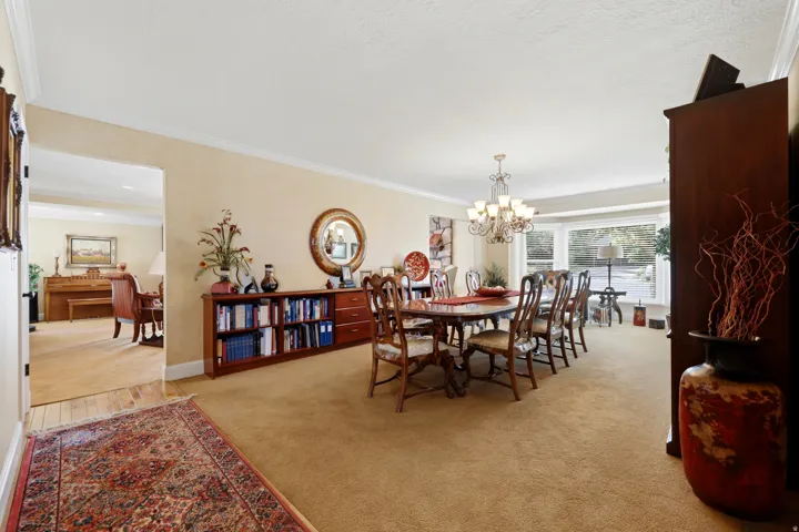 Formal dining area with an overhead chandelier, bay window, and crown molding