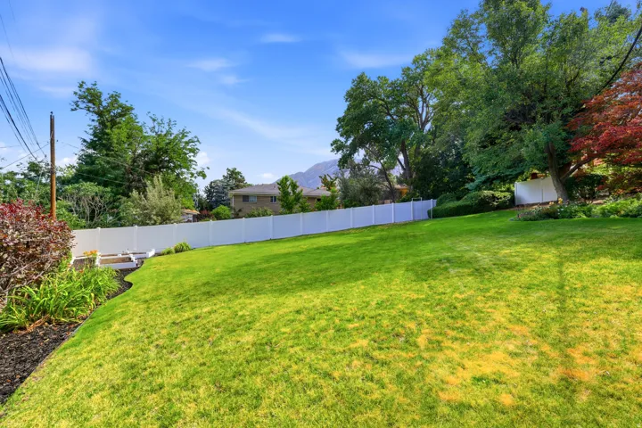 Expansive green lawn bordered by a white privacy fence