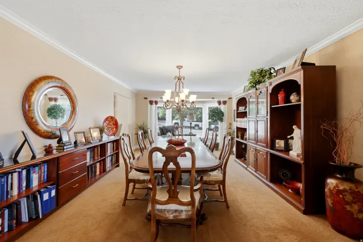 Dining area featuring a central chandelier, crown molding, and neutral wall tones