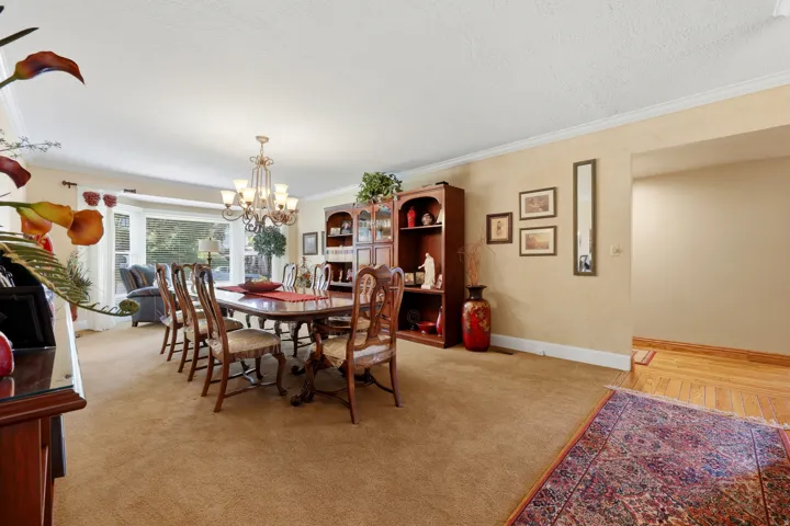 Expansive dining area featuring a large bay window, crown molding, and a built-in wood display cabinet