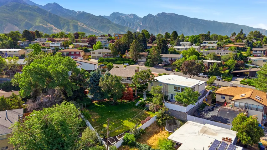 Expansive property with a verdant lawn, mature trees, and a mountain backdrop