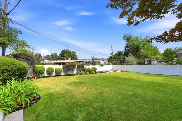 Expansive lawn area bounded by a white privacy fence