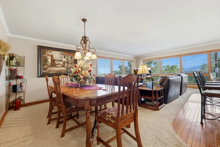 Dining area featuring a classic chandelier with glass shades, crown molding, and light-toned carpeting