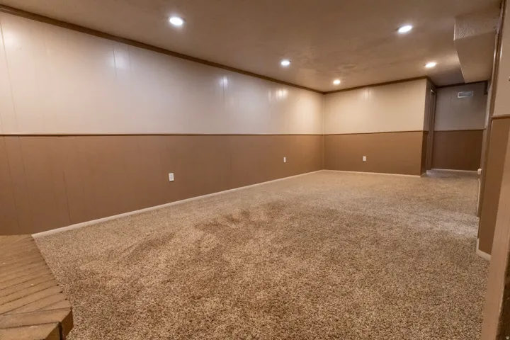 Spacious carpeted room featuring recessed lighting and two-tone paneling